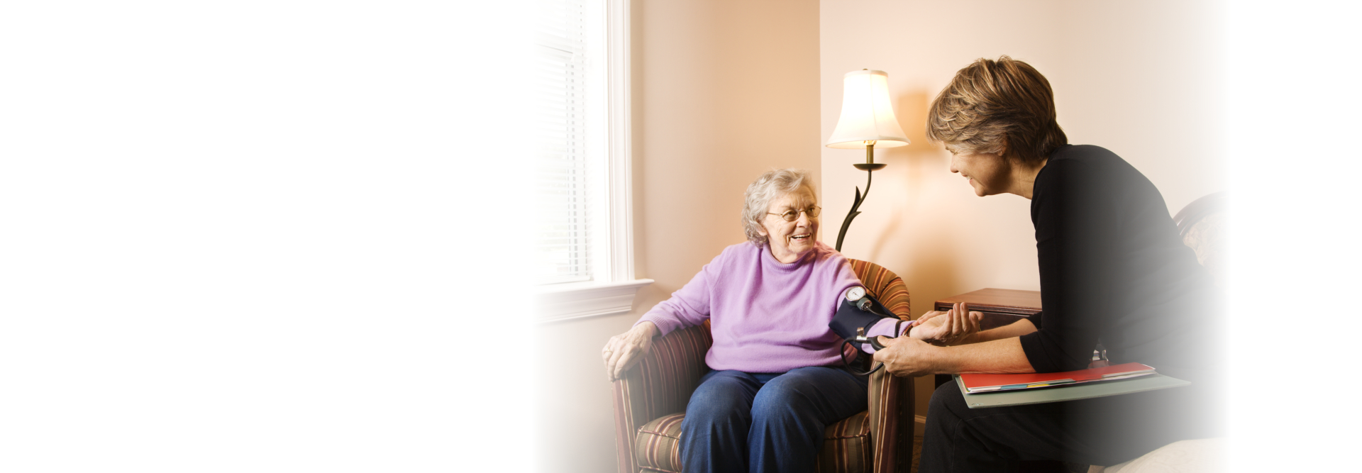 caregiver monitoring elderly woman's blood pressure