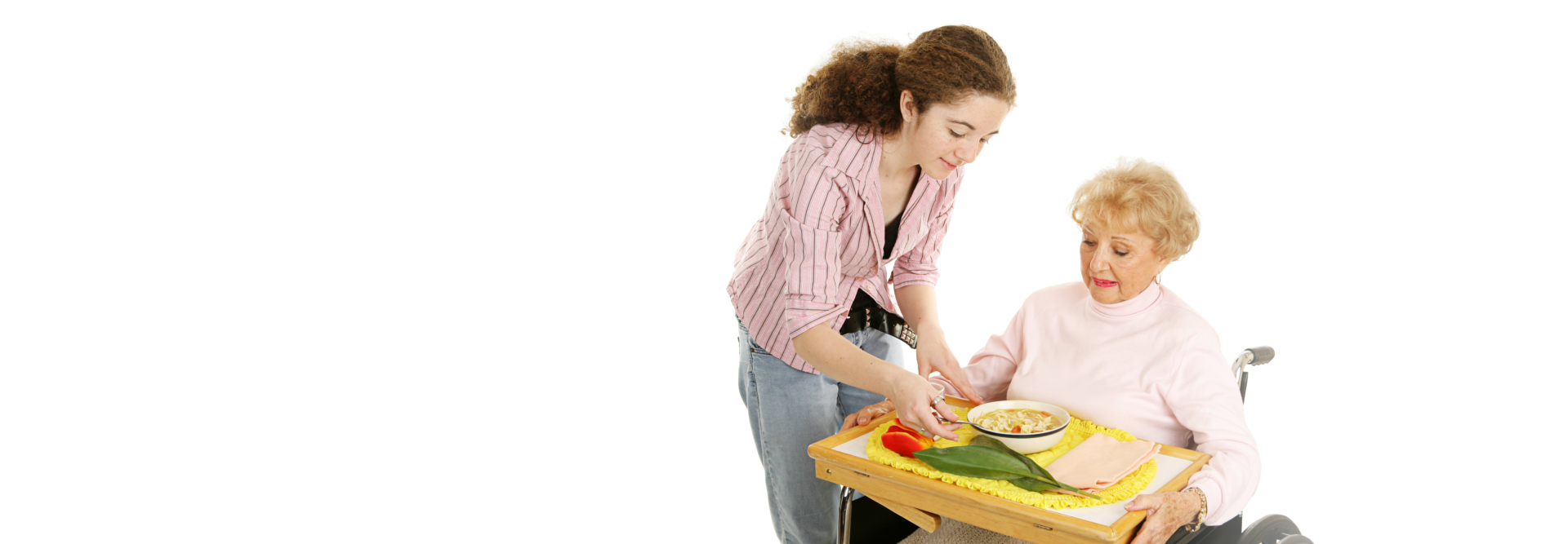 caregiver preparing meal for elderly woman